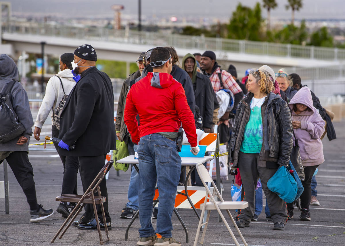 Homeless people line up the be screened as they enter the temporary shelter in the upper parkin ...
