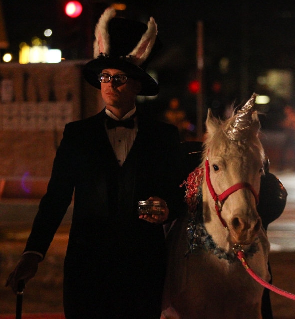 Artist Michael Barrett stands with Sparkles, a unicorn, as part of his performance piece during "The Traveling Miracle Show."