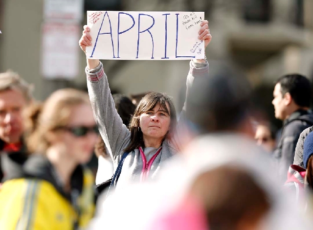 Justine Franco of Montpelier, Vt., holds up a sign near Copley Square in Boston looking for her missing friend, April, who was running in her first Boston Marathon on Monday. Two bombs exploded ne ...