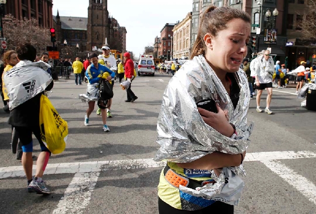 An unidentified Boston Marathon runner leaves the course crying near Copley Square following an explosion in Boston on Monday.