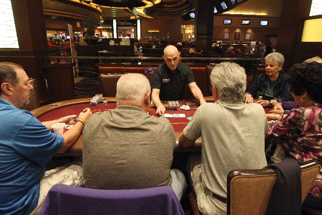 Dealer Joe Molinario, center, wears an Ultimate Poker shirt Friday in the poker room at Red Rock Resort. Ultimate Poker has registered thousands of users from every U.S. state and 20 different cou ...