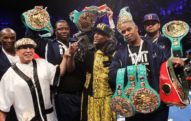 Floyd Mayweather Jr., center, poses with his championship belts and entourage Saturday after retaining his WBC welterweight title by beating Robert Guerrero by unanimous decision at the MGM Grand ...