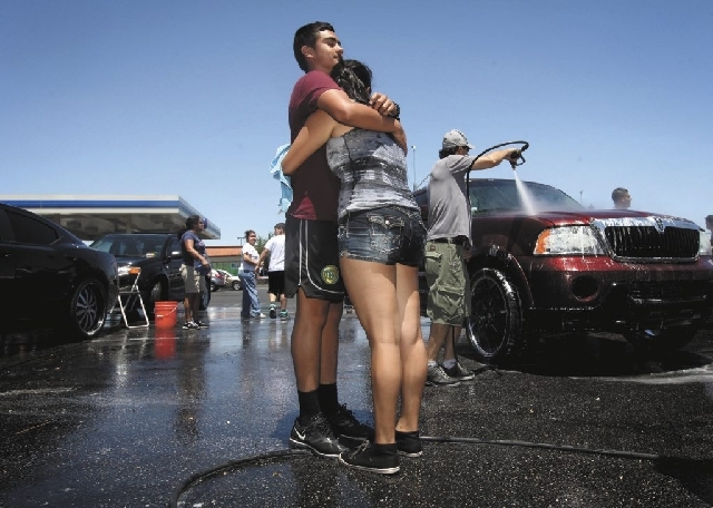 Victor De Leon, left, 17, and Janet Montes, 16, cousins of 15-year-old Marcos Arenas, hug at a benefit car wash Sunday at the intersection of Charleston Boulevard and Rainbow Boulevard. Dozens of  ...