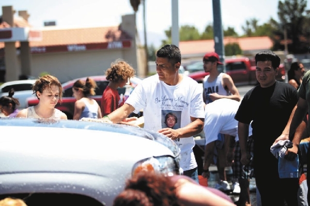Humberto Santoyo, center, godfather of Marcos Arenas, pitches in Sunday at a car wash to raise money for Marcos' funeral expenses.