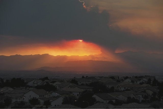 In this view looking west from Henderson, the sun sets behind a column of smoke created by a fire burning in the Carpenter Canyon area of Mt. Charleston on Tuesday. According to the BLM, the fire  ...