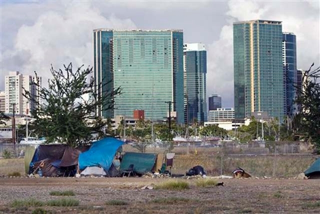 In this Monday, July 12, 2010 photo, the Honolulu skyline rises behind a homeless camp in an empty lot near Kaakako Park, in Honolulu.
