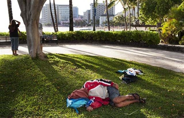 In this Friday, May 13, 2011 photo, a man sleeps on the ground near Waikiki Beach, in Honolulu.