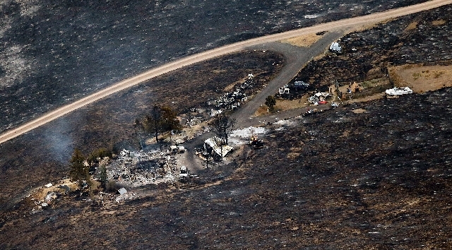 Burned foliage surrounds the remains of one of the homes burned by the wildfire Wednesday morning near Rockport, Utah. The fire, which appears to have been started by lightning, has burned about ...