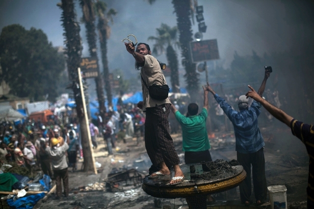 A supporter of ousted President Mohammed Morsi shoots a slingshot toward the Egyptian police on Wednesday during clashes in Cairo's Nasr City district Wednesday.