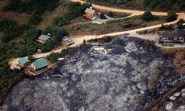 Untouched homes are next to the ashes of a home and blackened foliage near Rockport, Utah, Wednesday morning.