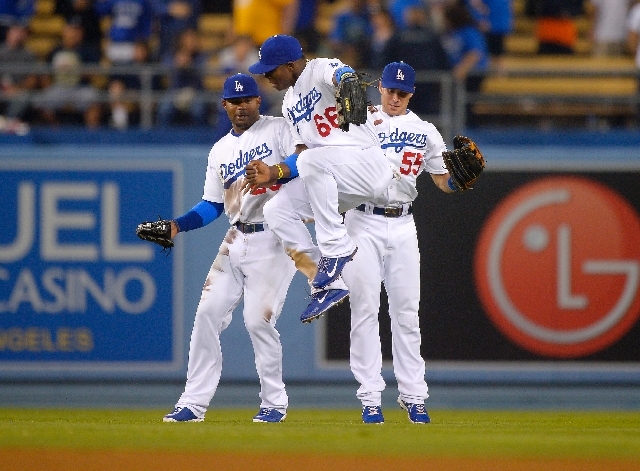 Dodgers outfielders Yasiel Puig (66), Skip Schumaker (55) and Carl Crawford celebrate Tuesday after Los Angeles' 4-2 win over the Mets. The Dodgers' 40-8 run has them leading their division by 7&f ...