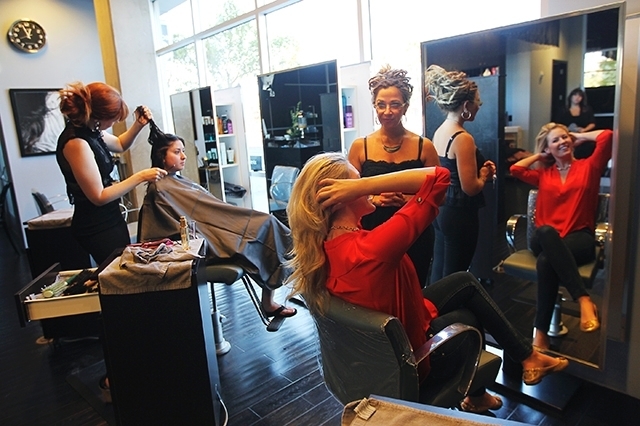Salon director Staci Linklater, standing right, and stylist Cassie Peters, far left, work with clients Aug. 10 at Globe Salon.