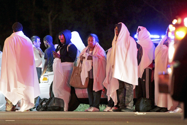Passengers of an overturned Greyhound bus stand near the scene, Saturday, Sept. 14, 2013, on interstate I-75 in Liberty Township, Ohio. Authorities say that at least 35 people have been hurt, with ...