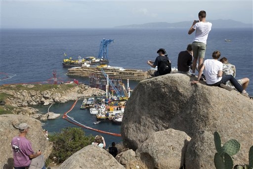 In this photo taken on Monday, Sept. 16, 2013 people take pictures of the Costa Concordia ship, on the Tuscan Island of Giglio, Italy, Wednesday, Sept. 18, 2013. For more than a year, tourists flo ...