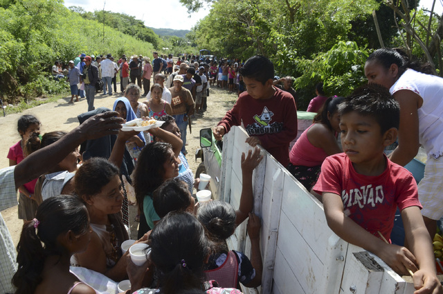 Villagers affected from the rains and floods caused by Tropical Storm Manuel line up to get a simple meal donated by residents of a nearby community in the village of Salsipuedes, Mexico, Friday, ...
