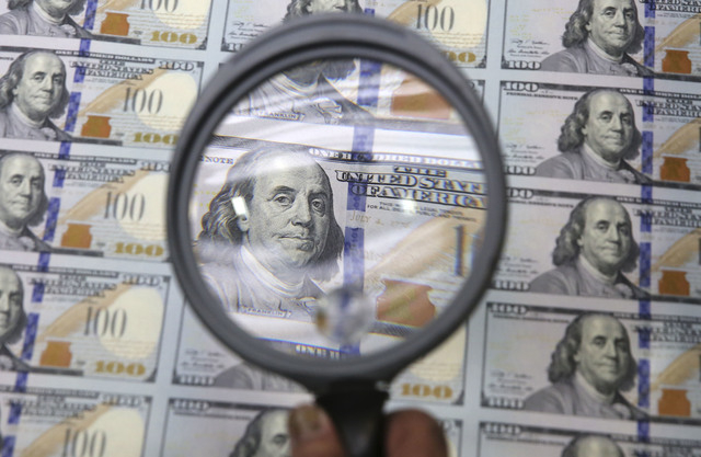 A sheet of uncut $100 bills is inspected during the printing process at the Bureau of Engraving and Printing Western Currency Facility in Fort Worth, Texas, Tuesday, Sept. 24, 2013.  The federal p ...