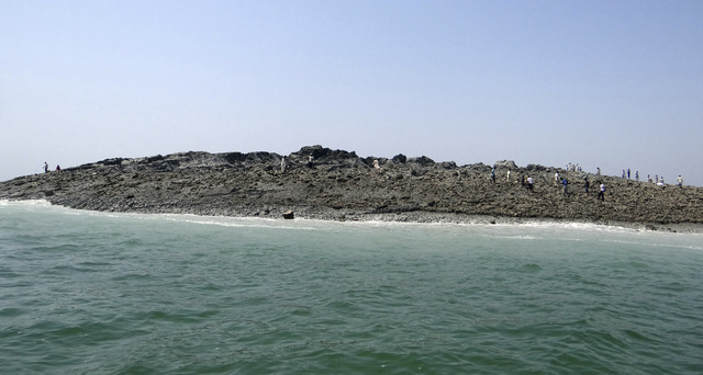 In this photo released by the Gwadar local government office on Wednesday, Sept 25, 2013, people walk on an island that reportedly emerged off the Gwadar coastline in the Arabian Sea. A deadly mag ...