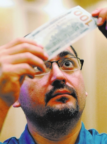 Gary Lussier from the Red Lake Gaming in Minnesota examines a new US $100. bill during G2E at the Sands Expo and Convention Center on Wednesday, Sept. 25, 2013. The newly redesigned note containin ...