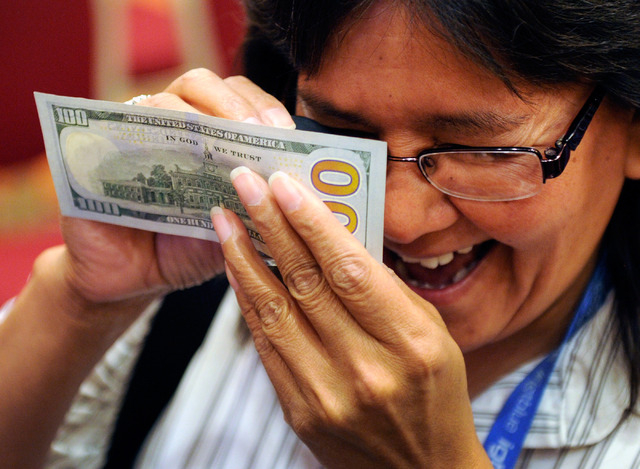 Donna Perkins from the Red Lake Gaming in Minnesota examines a new US $100. bill during G2E at the Sands Expo and Convention Center on Wednesday, Sept. 25, 2013. The newly redesigned note containi ...