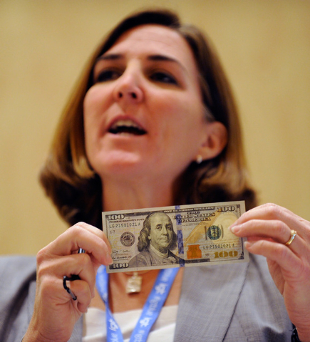 Lorelei Pagano, assistant director of the Division of Reserve Bank Operation and Payment Systems, displays a new US $100. bill during G2E at the Sands Expo and Convention Center on Wednesday, Sept ...