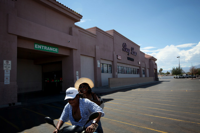 A pair rides a motor scooter past a Buy Low grocery store in Las Vegas Wednesday, Sep. 4, 2013. More popular grocery stores left standing in the West side, like Marios and Buy Low, located in the  ...