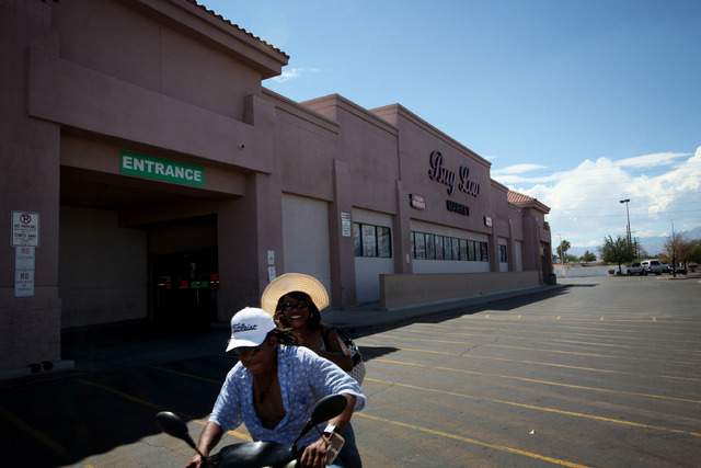 A pair rides a motor scooter past a Buy Low grocery store in Las Vegas Wednesday, Sep. 4, 2013. More popular grocery stores left standing in the West side, like Marios and Buy Low, located in the ...