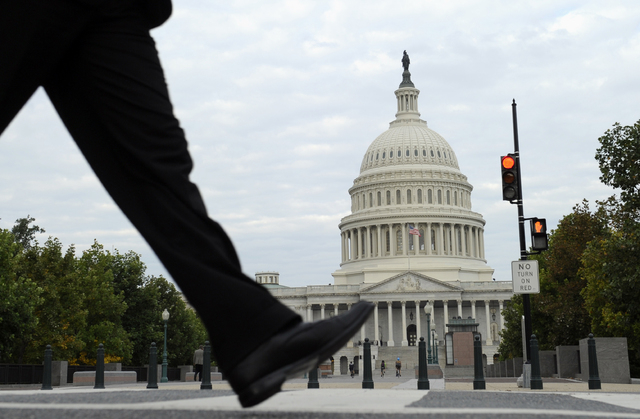 People walk near Capitol Hill in Washington, Tuesday, Oct. 1, 2013.  Congress plunged the nation into a partial government shutdown Tuesday as a long-running dispute over President Barack Obama's  ...