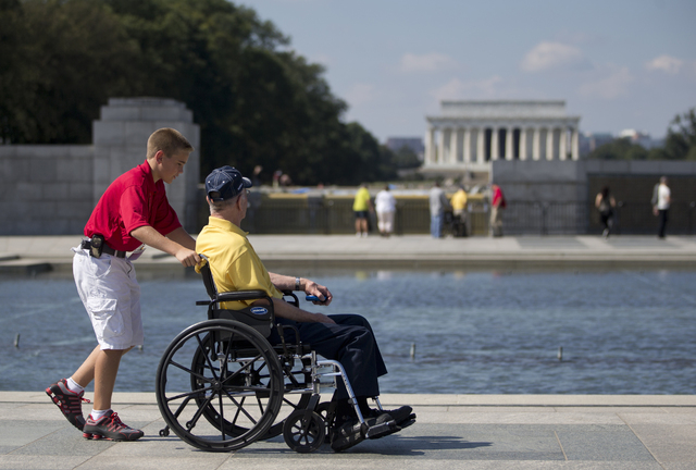 Korean War veteran Robert Olson, from Iowa, is pushed in his wheelchair by Zach Twedt, also from Iowa, around the National World War II Memorial in Washington, Tuesday, Oct. 1, 2013. Veterans who  ...