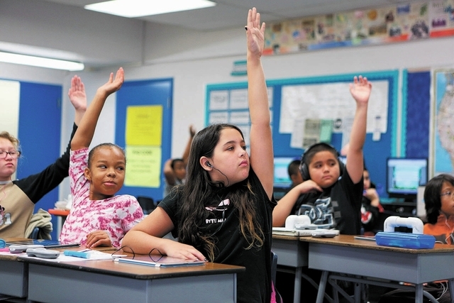 Aidan Patterson, center, pauses from working on an iPad to raise her hand with other students in Steve Armitage’s 5th grade class at Hancock Elementary School Friday, Oct. 18, 2013, in Las Vegas ...