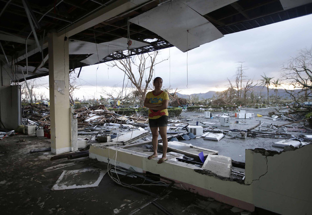 A woman stands amidst the devastation brought about by powerful Typhoon Haiyan at Tacloban city, in Leyte province, central Philippines Saturday Nov. 9, 2013. Rescuers in the central Philippines c ...