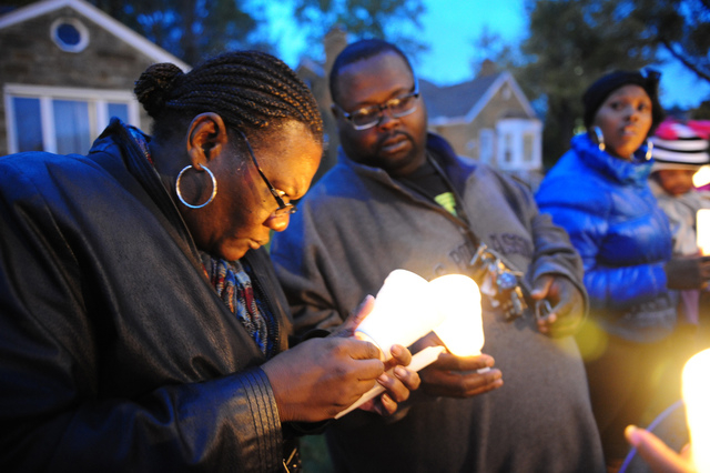 In this Nov. 6, 2013 file photo Charles Hannah lights Theresa Walker's candle, left, at a vigil for Renisha McBride in the front of the home where she was shot in Dearborn Heights, Mich. Prosecut ...