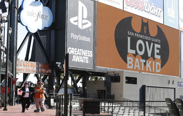 The scoreboard at AT&T Park displays a sign for Miles Scott, as Batkid, as the Penguin, bottom left, kidnaps San Francisco Giants mascot Lou Seal in San Francisco, Friday, Nov. 15, 2013. (AP Photo ...