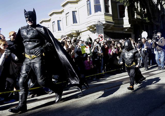 Miles Scott, dressed as Batkid, right, runs with Batman after saving a damsel in distress in San Francisco, Friday, Nov. 15, 2013. (AP Photo/Jeff Chiu)