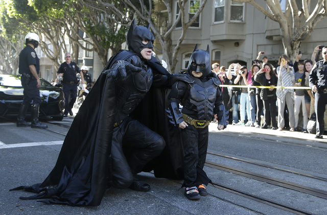 Miles Scott, dressed as Batkid, right, walks with Batman before saving a damsel in distress in San Francisco, Friday, Nov. 15, 2013. (AP Photo/Jeff Chiu)