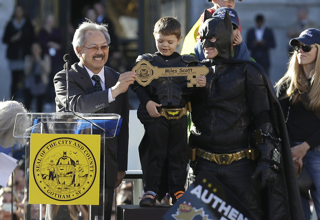 Miles Scott, dressed as Batkid, stands next to Batman as he receives the key to the city from San Francisco Mayor Ed Lee, left, at a rally outside of City Hall in San Francisco, Friday, Nov. 15, 2 ...