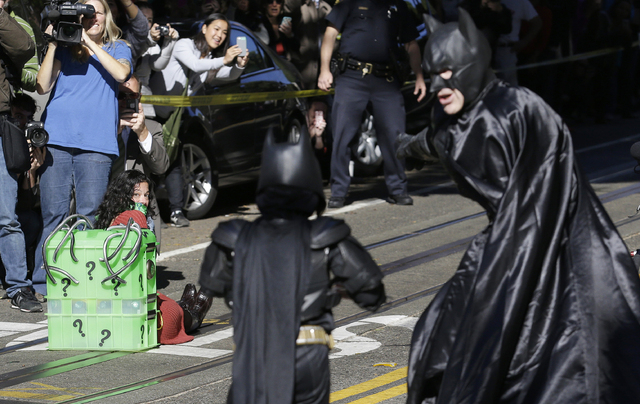 Miles Scott, dressed as Batkid, center, walks with Batman to save a damsel in distress on the Cable Car line in San Francisco, Friday, Nov. 15, 2013. (AP Photo/Jeff Chiu)