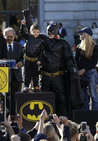 Miles Scott, dressed as Batkid, second from left, raises his arm next to Batman at a rally outside of City Hall with Mayor Ed Lee, left, and his mother Natalie Scott in San Francisco, Friday, Nov. ...