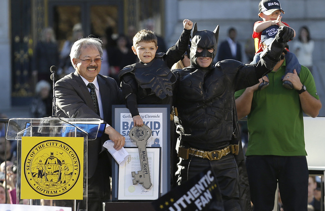 Miles Scott, dressed as Batkid, second from left, raises his arm next to Batman at a rally outside of City Hall with Mayor Ed Lee, left, and his father Nick and brother Clayton, at right, in San F ...