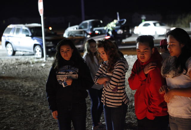 People look at a memorial for 14-year-old Helen Liu, who was killed last weekend, as floodlights illuminate a three-car crash behind them at the corner of Blue Diamond Road and Cimarron Road in La ...