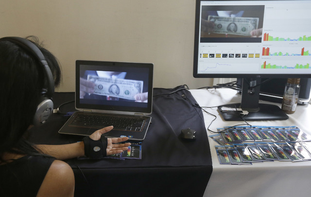 Jenn de la Vega wears a device on her hand as she gives a demonstration on a Technicolor mobile app that measures analytics for emotional response to content that will give feedback to the content ...