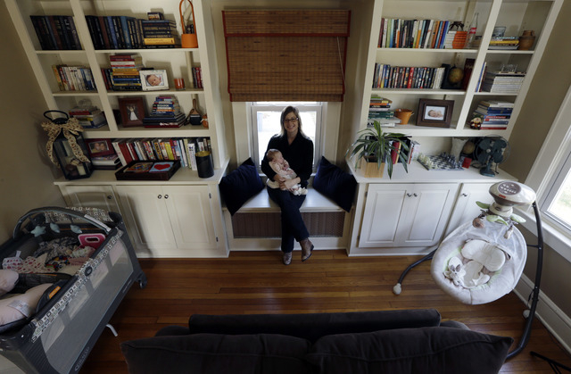 In this photograph taken Thursday, Nov. 21, 2013, Abigail Ernst poses for The Associated Press with her 2-month-old daughter, Lucy, in their Oldwick, N.J. home. Ernst, and her husband, Ken Ernst, ...