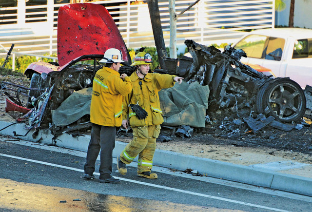 Sheriff's deputies work near the wreckage of a Porsche that crashed into a light pole on Hercules Street near Kelly Johnson Parkway in Valencia, Calif., on Saturday, Nov. 30, 2013. A publicist for ...
