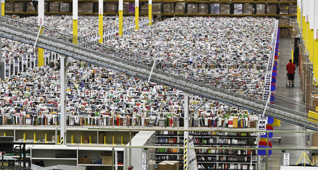 In this  Monday, Nov. 26, 2012, file photo, an employee walks a wide isle at Amazon.com's 1.2 million square foot fulfillment center, in Phoenix.  Millions of shoppers are expected to click on ite ...