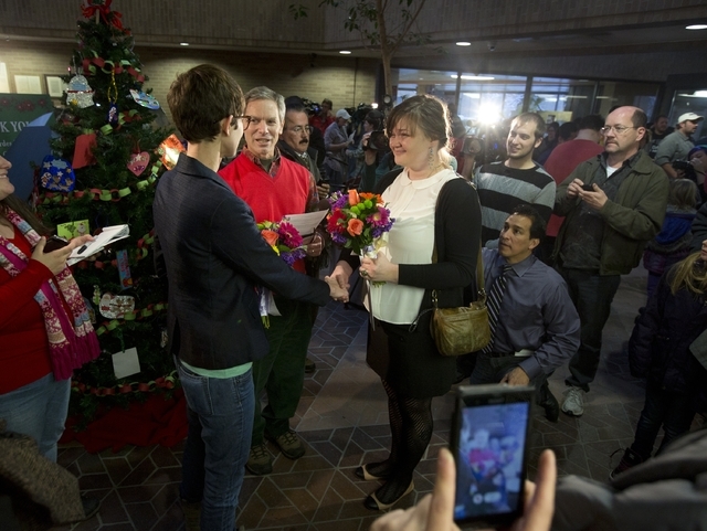 Natalie Dicou, left, and Nicole Christensen, right, are married by Salt Lake City Mayor Ralph Becker, middle, in the lobby of the Salt Lake County Clerk's Office in Salt Lake City on Friday, Dec. ...