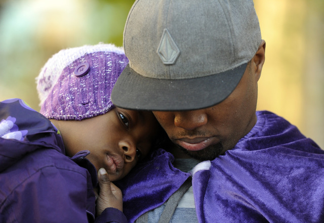 Quinton Reynolds, of Emeryville, wears a purple cape as he holds his daughter Qniyah Reynolds, 4, as he gathers with others outside of Children's Hospital Oakland in support of Jahi McMath in Oakl ...