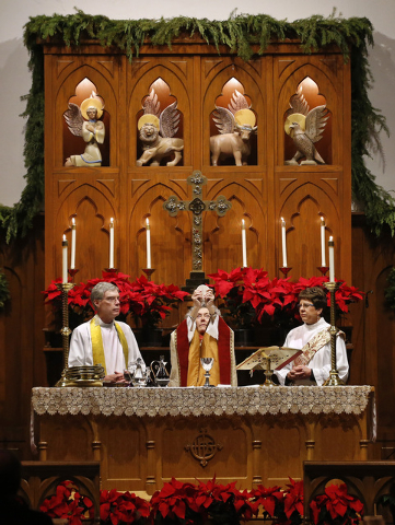 The Rev. Susan W. Springer raises and halves a wafer representing the body of Christ as she presides over a special late night Christmas mass at St. John's Episcopal Church, just after midnight on ...