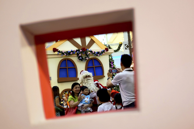Shoppers pose for photos with a man in Santa Claus costume on Christmas day at a shopping mall in Kuala Lumpur, Malaysia, Wednesday, Dec. 25, 2013. (AP Photo/Daniel Chan)