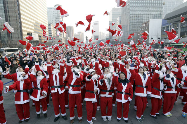 More than 1,000 volunteers clad in Santa Claus costumes throw their hats in the air as they gather to deliver gifts for the poor in downtown Seoul, South Korea, Tuesday, Dec. 24, 2013. (AP Photo/L ...