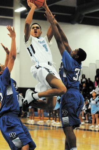 Canyon Springs Jordan Davis (3) takes a shot against Desert Pines Jordan Simon (32), right, and Coby Myles (15) at home, Thursday, Dec. 5, 2013. Canyon Springs won the game 66-61 against the Jagua ...