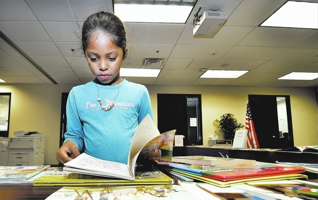 First-grader Neena Elisarraras looks at some books during a book exchange Nov. 18 at Nevada Virtual Academy. (Bill Hughes/View)
